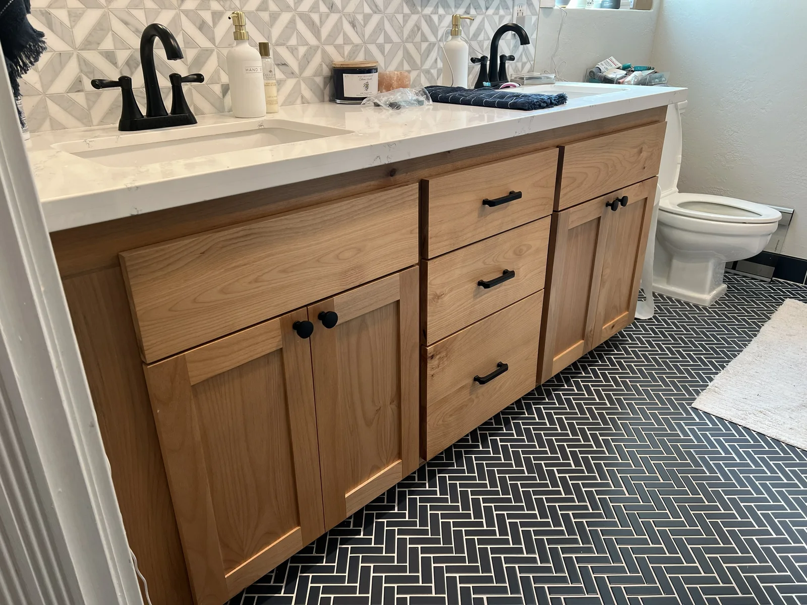 Wood bathroom vanity with two sinks, a white countertop, and black cabinet hardware