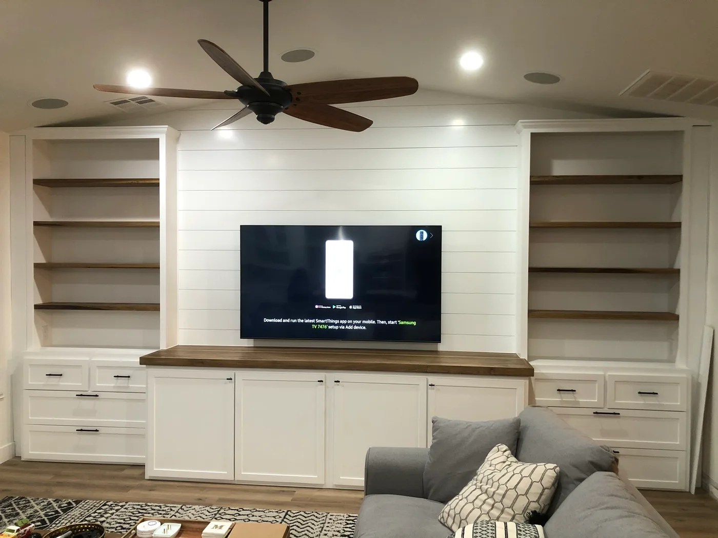 White media wall with open shelving, lower cabinets, and a central television