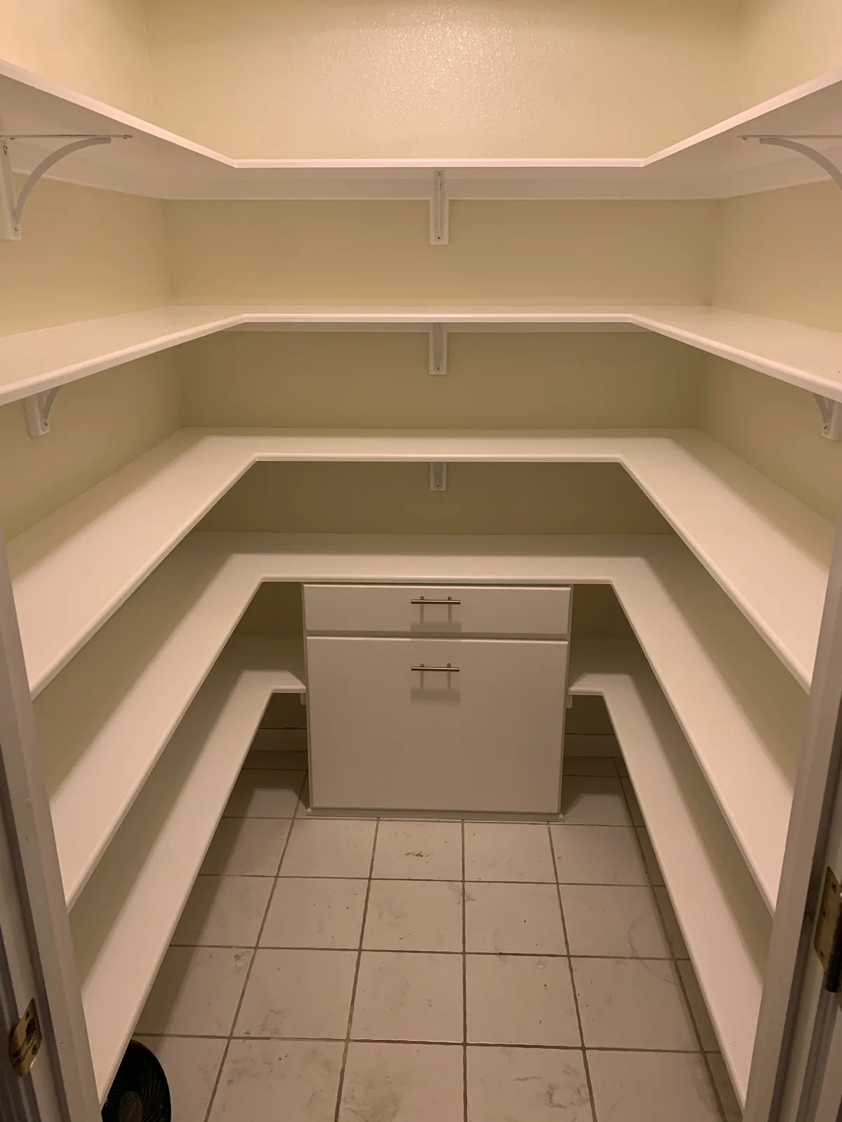 Walk-in pantry with white wraparound shelves and a lower drawer cabinet
