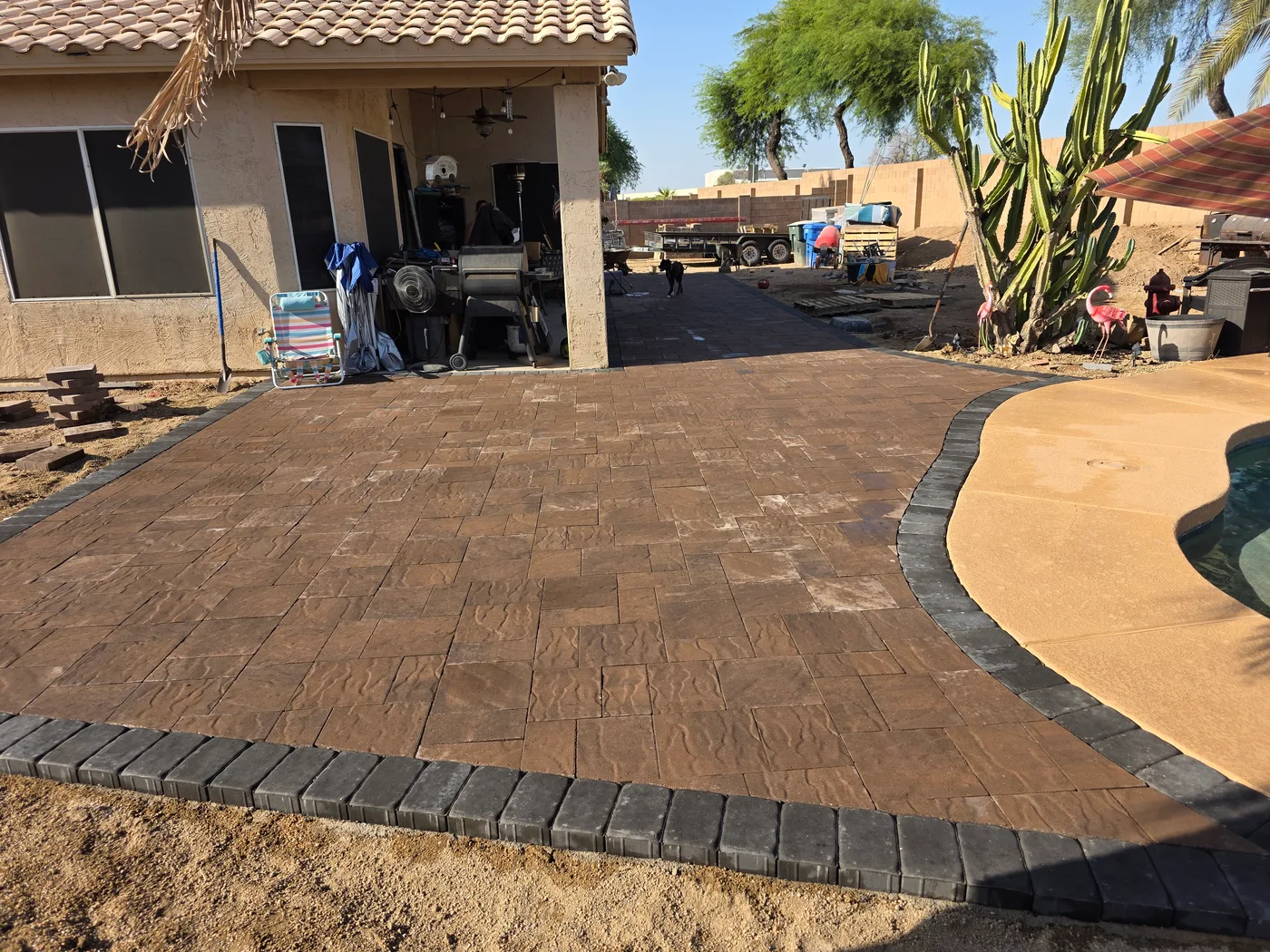 Paver patio with a curved dark border beside an outdoor living area