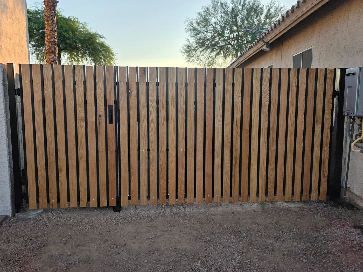 Double gates with vertical wood slats in dark metal frames